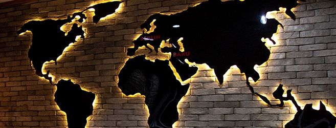 World map signage in black with orange LED halo illumination