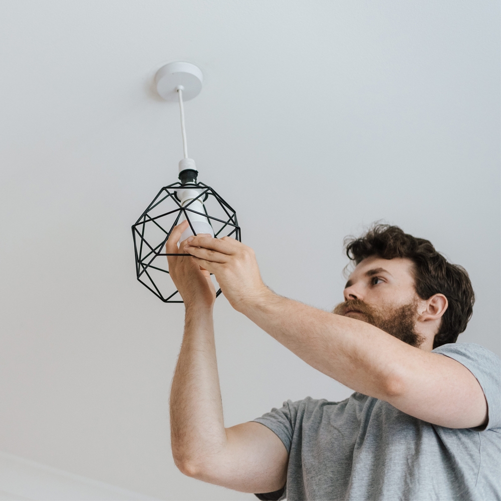 Person changing a light bulb to LED in a pendant light fitting